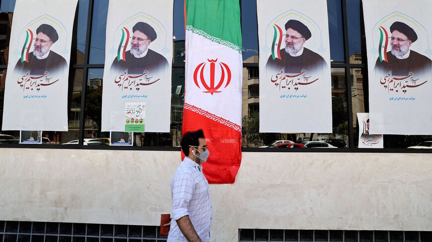An Iranian man walks by posters of presidential candidate Ebrahim Raisi outside a campaign office in Tehran on June 7, 2021.
