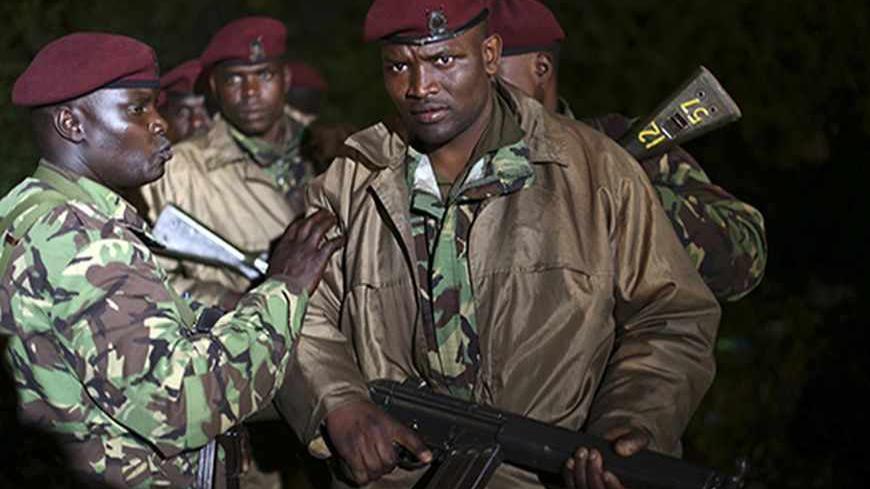 Kenyan soldiers hold their rifles near the Westgate shopping centre in Nairobi September 23, 2013. Thick smoke poured from the besieged Nairobi mall where Kenyan officials said their forces were closing in on Islamists holding hostages on Monday, three days after a raid by Somalia's al Shabaab killed at least 62 people. It remained unclear how many gunmen and hostages were still cornered in the Westgate shopping centre, two hours after a series of loud explosions and gunfire were followed by a plume of blac