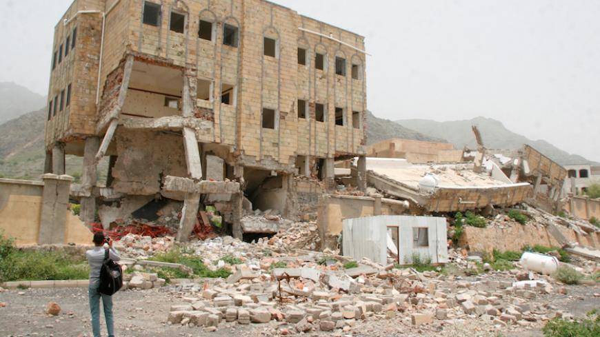 A journalist takes photos of a school destroyed by a Saudi-led air strike in the southwestern city of Taiz, Yemen July 27, 2016. REUTERS/Anees Mahyoub - RTSJWDA