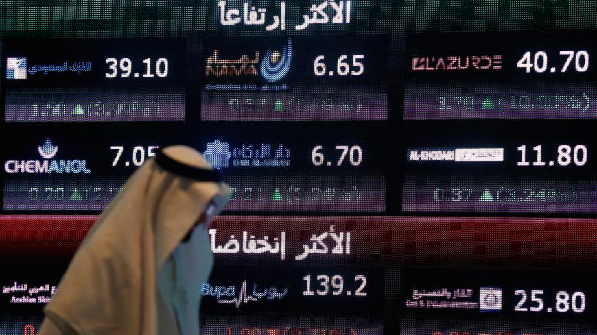 An investor walks past a screen displaying stock information at the Saudi Stock Exchange (Tadawul) in Riyadh, Saudi Arabia June 29, 2016. REUTERS/Faisal Al Nasser - S1AETMRJVXAC